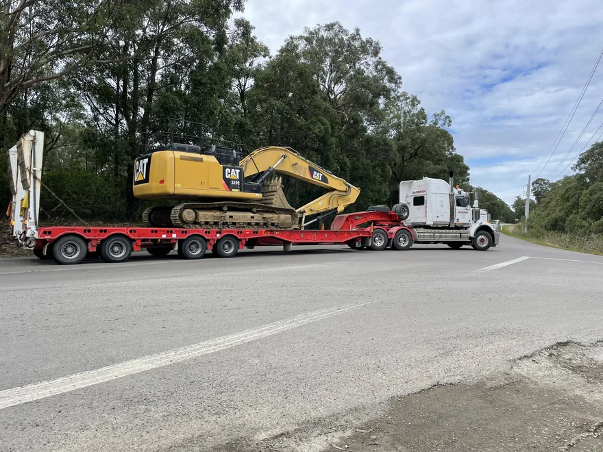 Excavator loaded on a low-loader beside the road