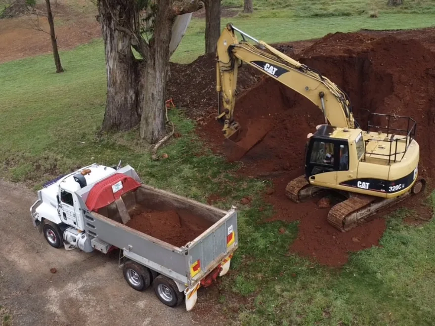 Excavator loading a tipper truck from a fresh cut
