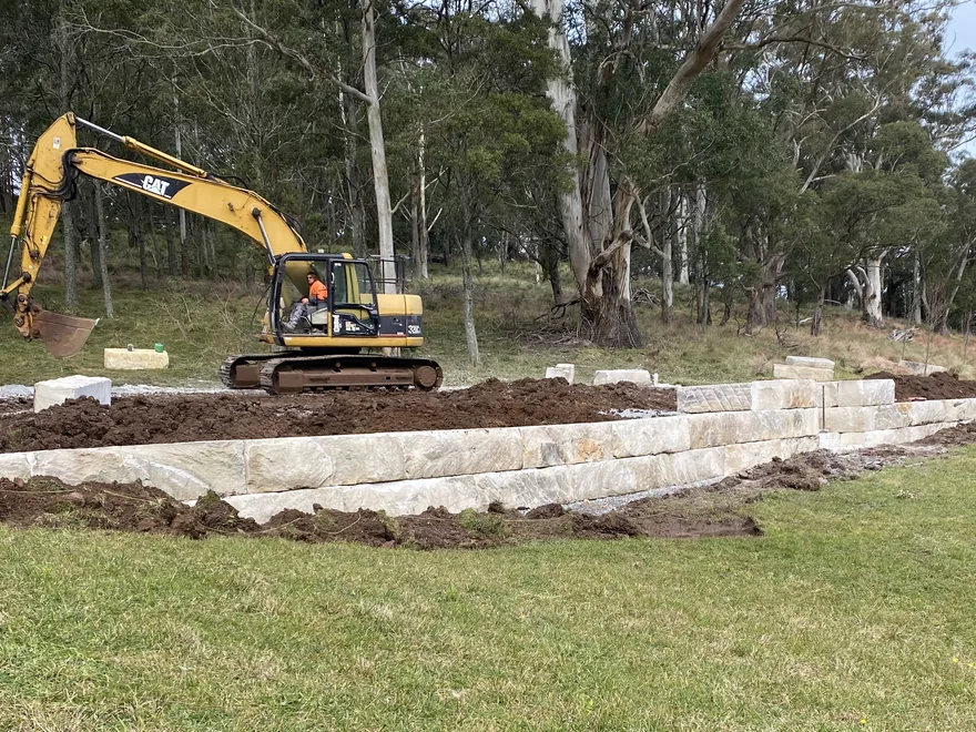 Sandstone block retaining wall being built with an excavator